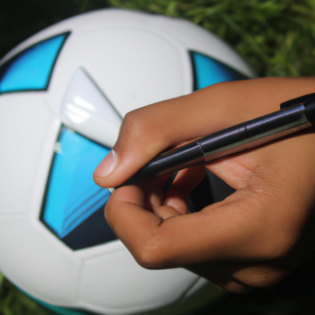 Person holding football and pen
